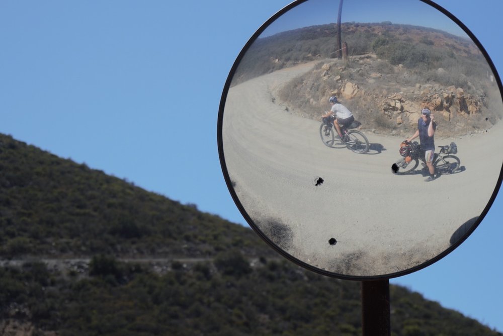 Reflection of Caitlin and Devon climbing hill in Baja